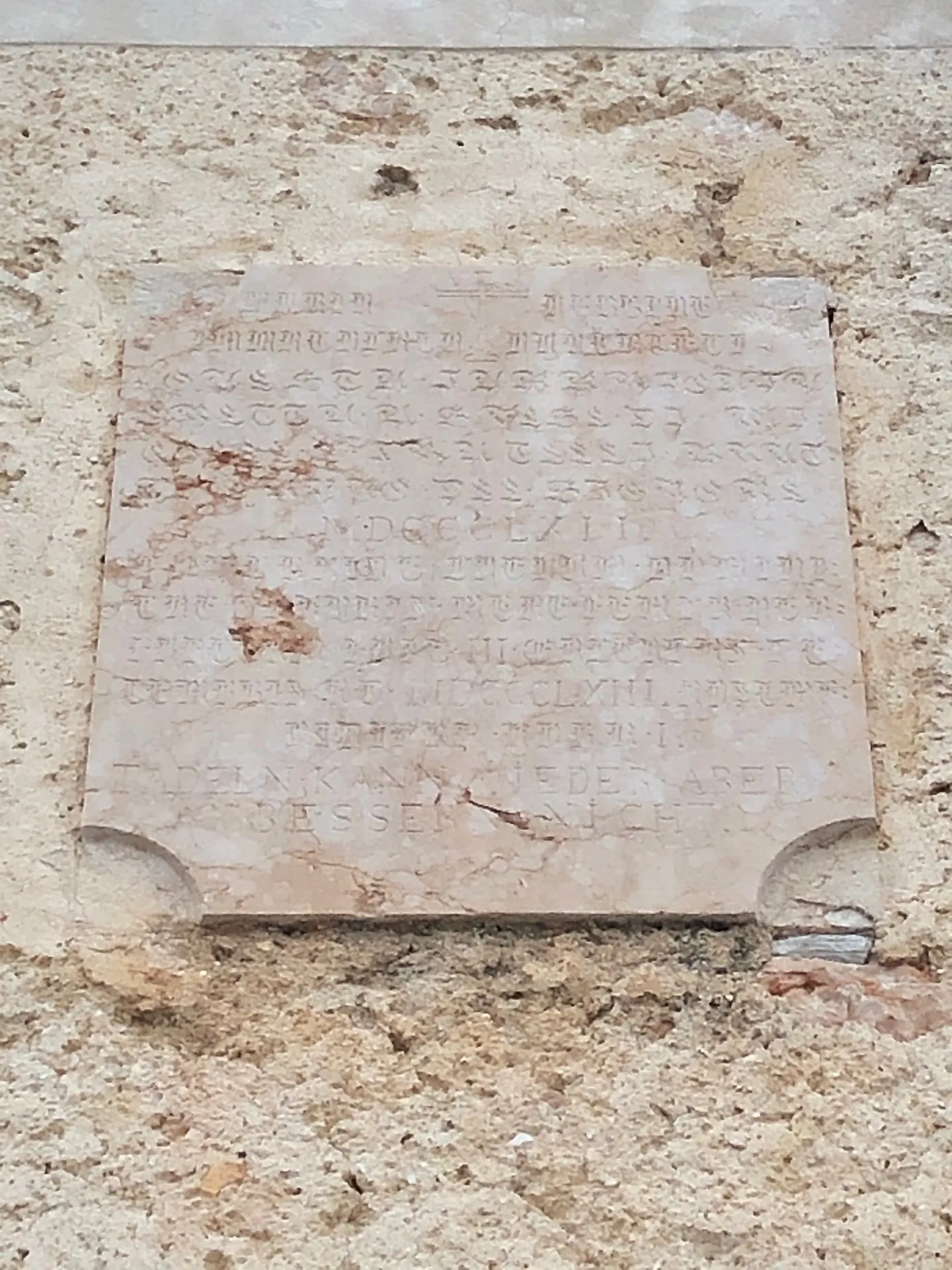 Lapide antica sulla facciata con iscrizione multilingue